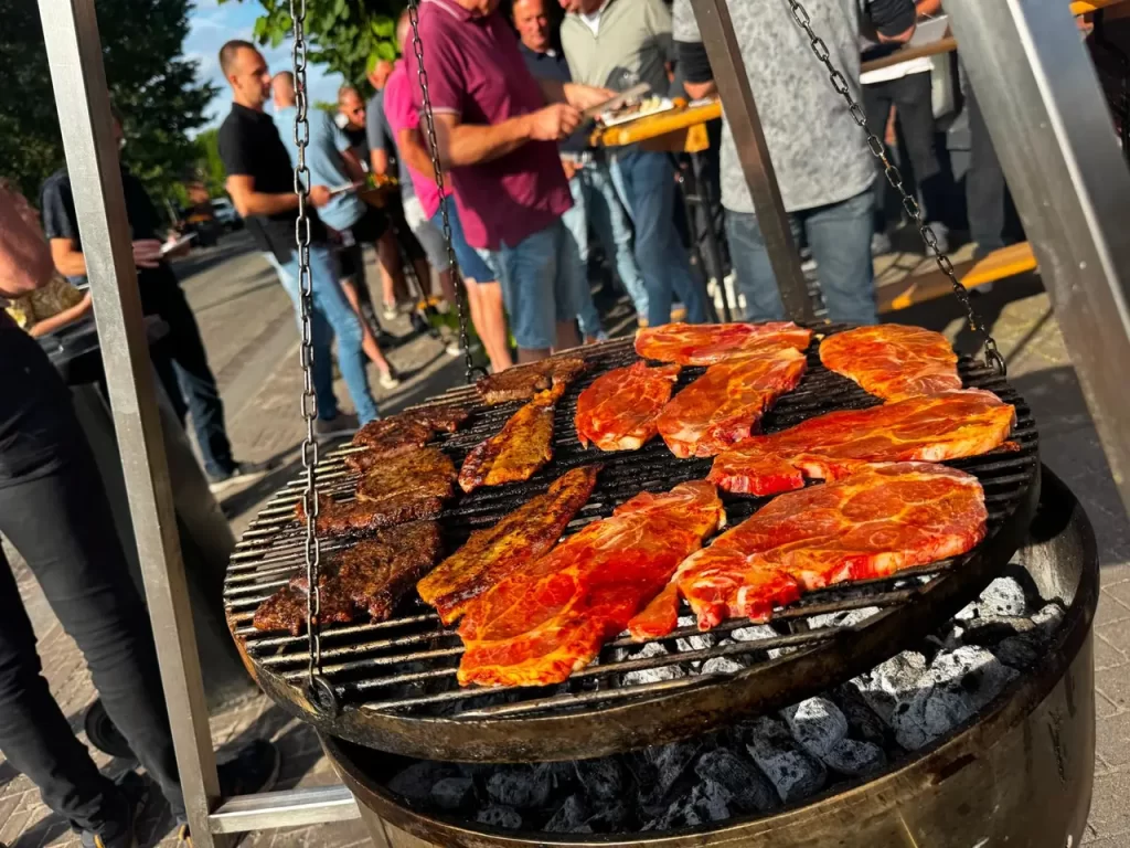 Vlees op de houtskoolbarbecue tijdens een feest, gasten op de achtergrond