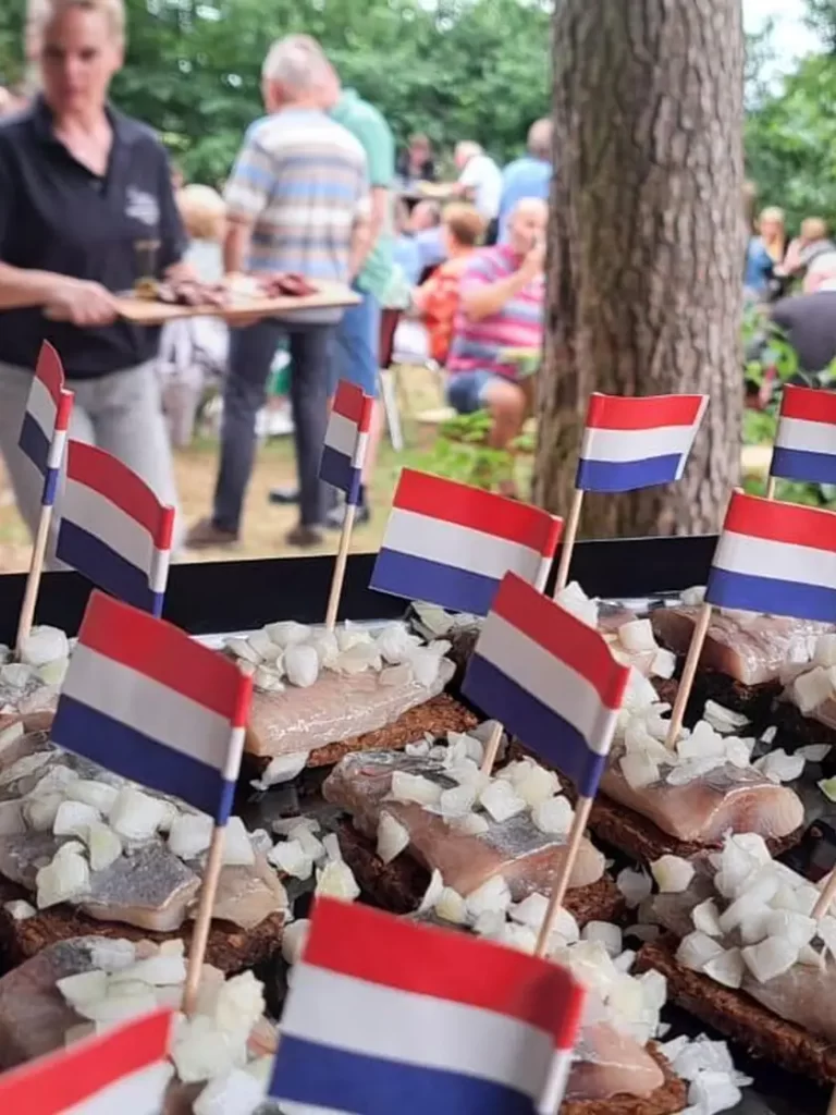 Gasten aan lange tafels in het bos bij een buffet